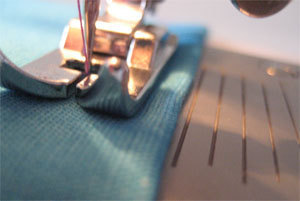 An up-close look at a sewing machine threading fabric.