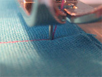 An up-close look at a sewing machine stitching red.