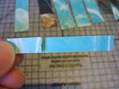 A person holds up a tiny strip of ripped blue paper.