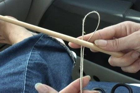 A looped piece of string held against a small dowel rod.