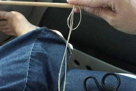 A person pulls on a string from near their blue jeans.