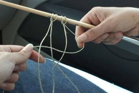 Hands are holding a stick with string hanging from it.