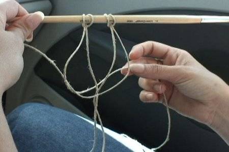 A woman's hands displaying looped string on a stick.
