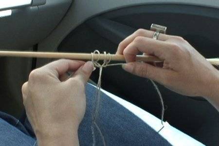 A person is twisting string around a stick.