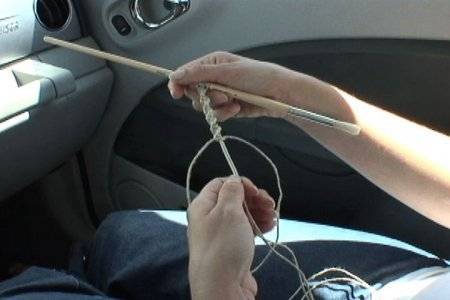 A person knitting with yarn in a car.