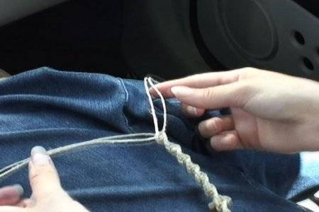 A woman's hands holding string that is twisted together.