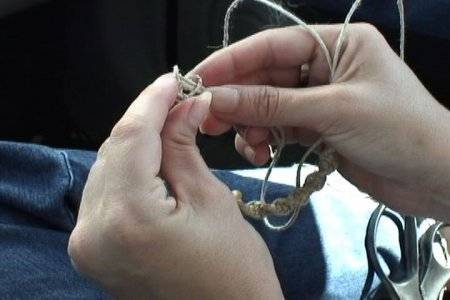A person in blue jeans works with some string.