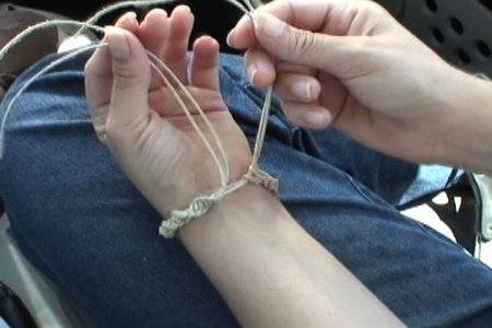 A person is tying a string around their wrist.