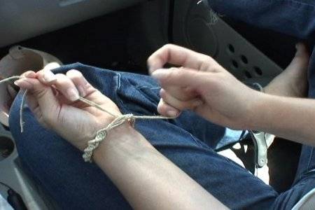 A person tying a string around their left wrist.