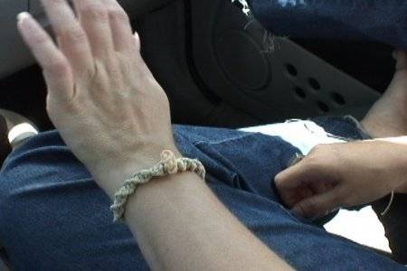 A person is holding up their left hand with a bracelet on it.