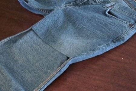 A pair of blue jeans with the front part of the leg cut off in a square.