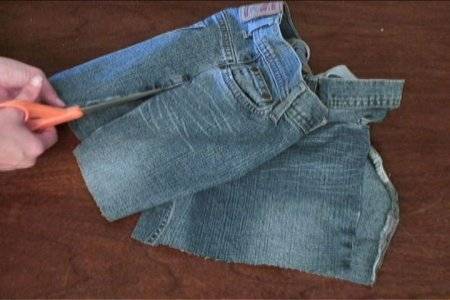 ''A person cuts a pant using sissors, to make overalls".
