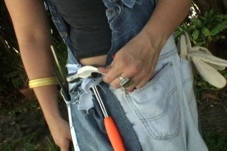 Man holding a power tool in his jeans belt with an orange handle on it.