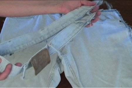 Woman cut the top belt of the jean pant.