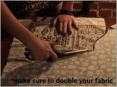 Woman cutting fabric by placing paper cutting with the help of scisser.