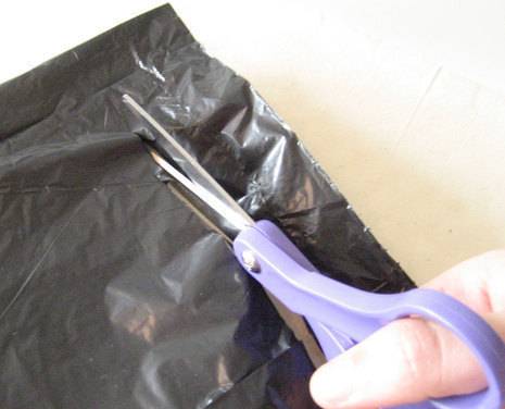 A black colour carry bag is cutting with a lavender scissors.