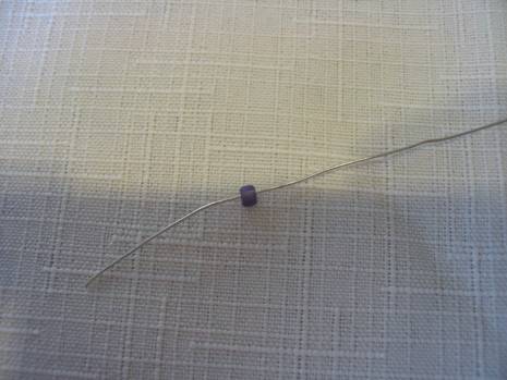 Steel wire is placed into a black bead placed on fabric.