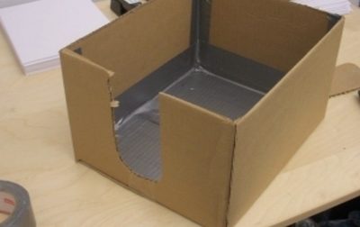 Cardboard box with cutout on one side and duct taped interior