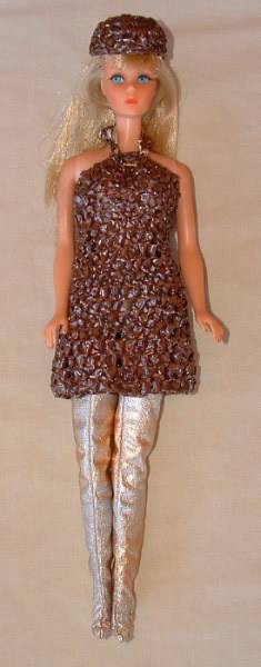 A fashion doll similar to a Barbie doll is dressed in a 1960s glittery dress and hat with leggings.