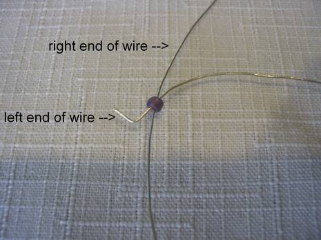 Two ends of a wire are put through a purple bead.