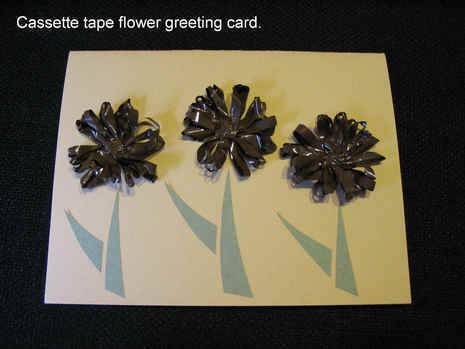 Three abstract flower forms on a greeting card, with the flower petals created by loops of black cassette tape.