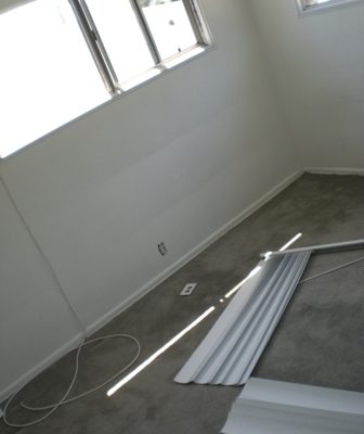 An unfinished room with narrow sliding windows and carpet.