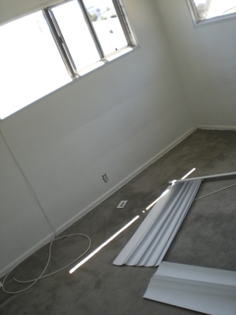 An unfinished room with narrow sliding windows and carpet.