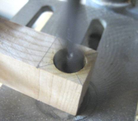 Drill cutting hole in block of wood.