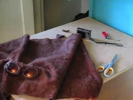 Dark cloth fitted with goggles lying on the table with scissors and other tools.