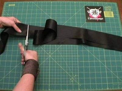 A person is cutting a length of black ribbon.