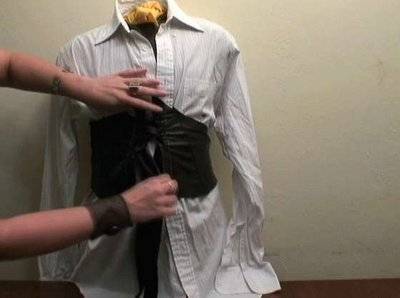 A person fitting a corset on a mannequin.