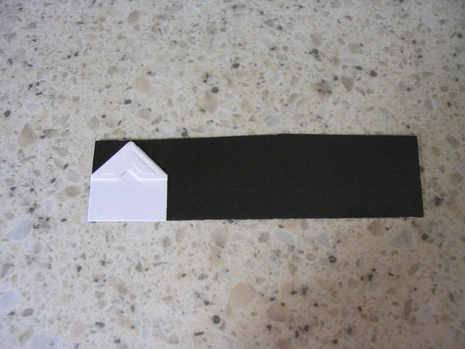 A white house is made on a paper on a black paper.