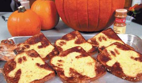 Slices of bread sit in a tray near pumpkins.