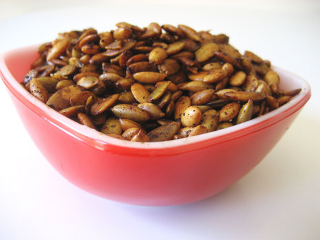 Pumpkin seeds sitting inside an ellipsoid bowl.