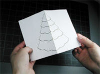 A person is explaining how to make a christmas tree pop-up card.