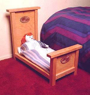 A doll in a crib next to a bed.