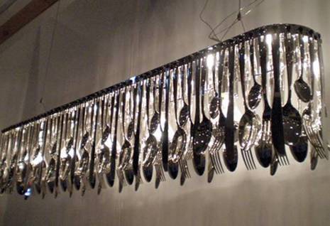 A long hanging chandlier made of silverware.