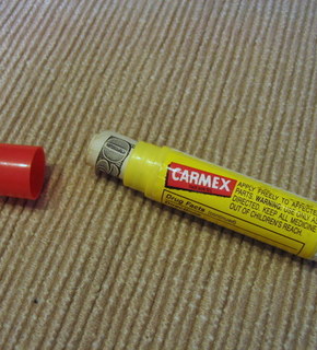The cap is off of a bottle of Carmex.
