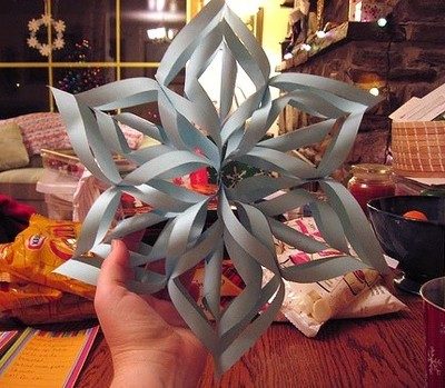 A person is showing gray color 3-D paper snowflake.