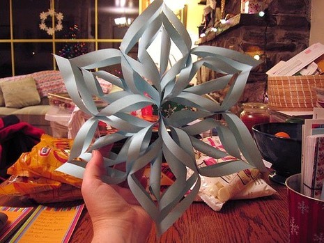 A person is showing gray color 3-D paper snowflake.