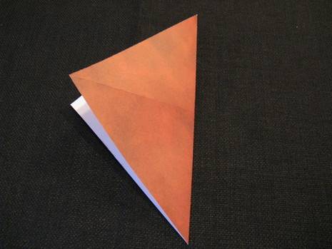 A piece of paper that is red on one side folded into a triangle shape.