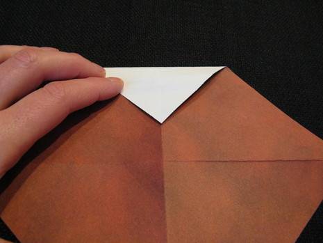 A person is folding down the corner of a brown and white paper.