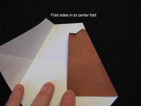 Person folding some paper that is white on one side and red on the other.