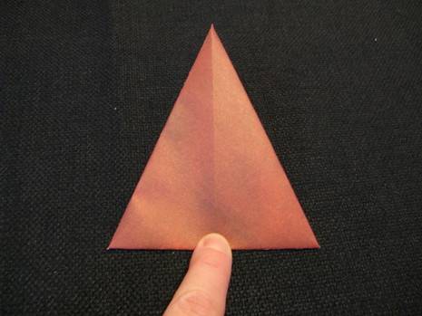 A person folding paper like triangle to make paper Santa for Christmas.