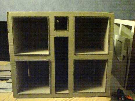 A cube made of cardboard with square and rectangular sections in inside it.