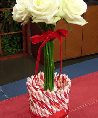 A candycane vase with a bouquet of flowers inside.
