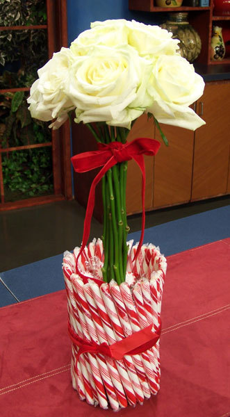 A candycane vase with a bouquet of flowers inside.