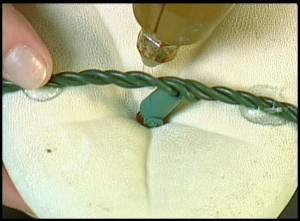 A person is gluing serial light wires to sheets to make sea biscuit lights.