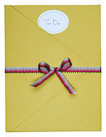A red and blue bow is on a yellow envelope.