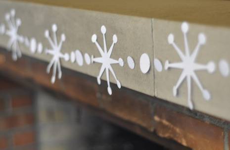 Snowflake garland made from paper, hanging over a fireplace.